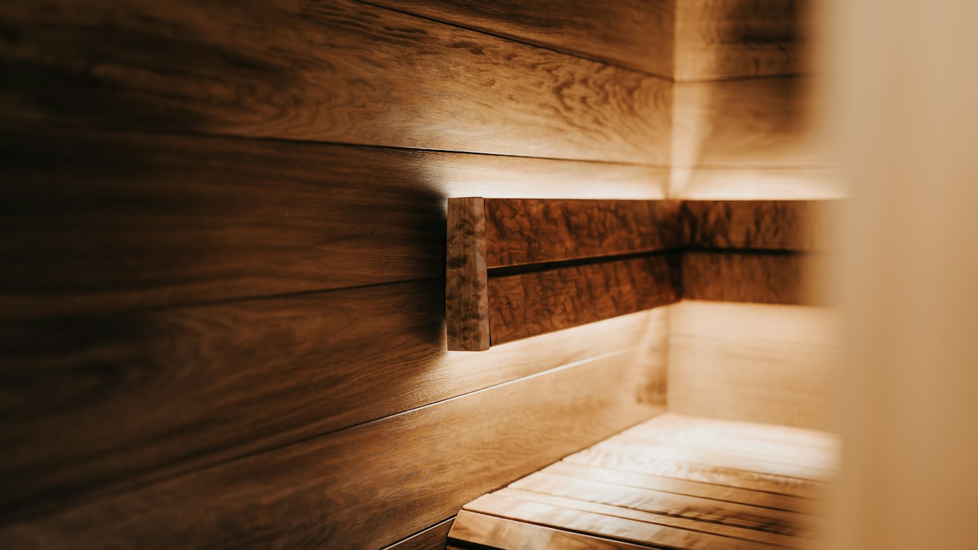 Warmly lit wooden sauna interior with horizontal planks and benches.